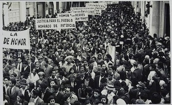 Fotografía en blanco y negro de una multitud congregada en una calle con carteles y pancartas con mensajes políticos