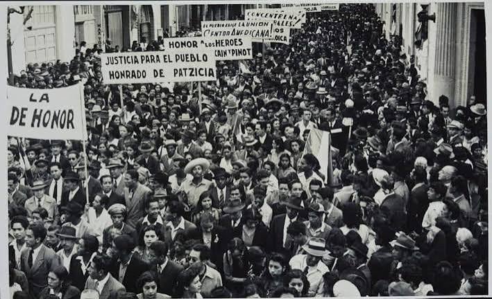 Una multitud marcha por una calle urbana con pancartas que exigen justicia en el contexto de las movilizaciones de la Revolución de Guatemala de 1944. (Diario de Centroamerica )