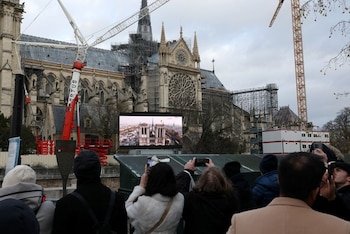Un grupo de personas toma fotografías frente a una pantalla en una zona pública para ver la ceremonia de reapertura de la catedral de Notre Dame de París. Fue el 7 de diciembre de 2021
(REUTERS)