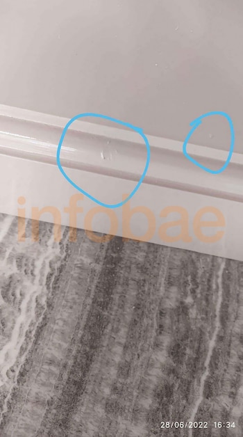Un primer plano del borde blanco de un mueble marcado con dos círculos azules sobre un piso de granito gris