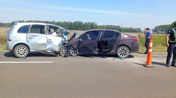 Dos automóviles colisionados en una carretera junto a un cono de tránsito naranja y personal policial sobre el asfalto