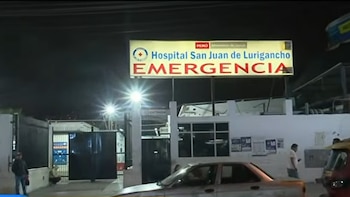 Letrero luminoso del área de emergencia del Hospital San Juan de Lurigancho en la noche, con un automóvil y personas frente al ingreso