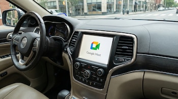 Vista del interior de un coche mostrando el logo de Google Meet en la pantalla de infoentretenimiento. Se observa el volante de un Jeep y el salpicadero.