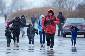 Migrantes corren bajo la lluvia