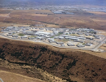 Vista aérea de un complejo penitenciario con múltiples edificios, carreteras internas, zonas de aparcamiento y cercas perimetrales en un terreno árido