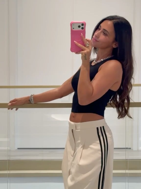 Antonela Roccuzzo posa frente a un espejo con un top negro y un pantalón claro para compartir su estilo en redes sociales.