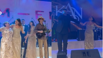 Personas vestidas de gala bailan en un escenario junto a un guitarrista con sombrero y un cantante con gafas oscuras frente al logotipo KAN