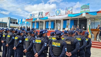 Un grupo de agentes de policía y personas de civil posan alineados frente a un edificio con banderas de Guatemala