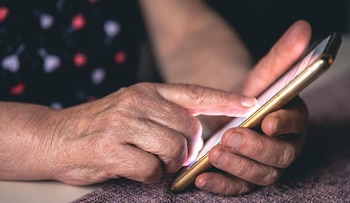 Manos de una persona sostienen un teléfono inteligente y presionan la pantalla con un dedo