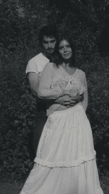 Retrato en blanco y negro de María Levy y Gabriel Stavenhagen. Él la abraza por la espalda mientras ella mira a cámara con una leve sonrisa, con follaje oscuro de fondo