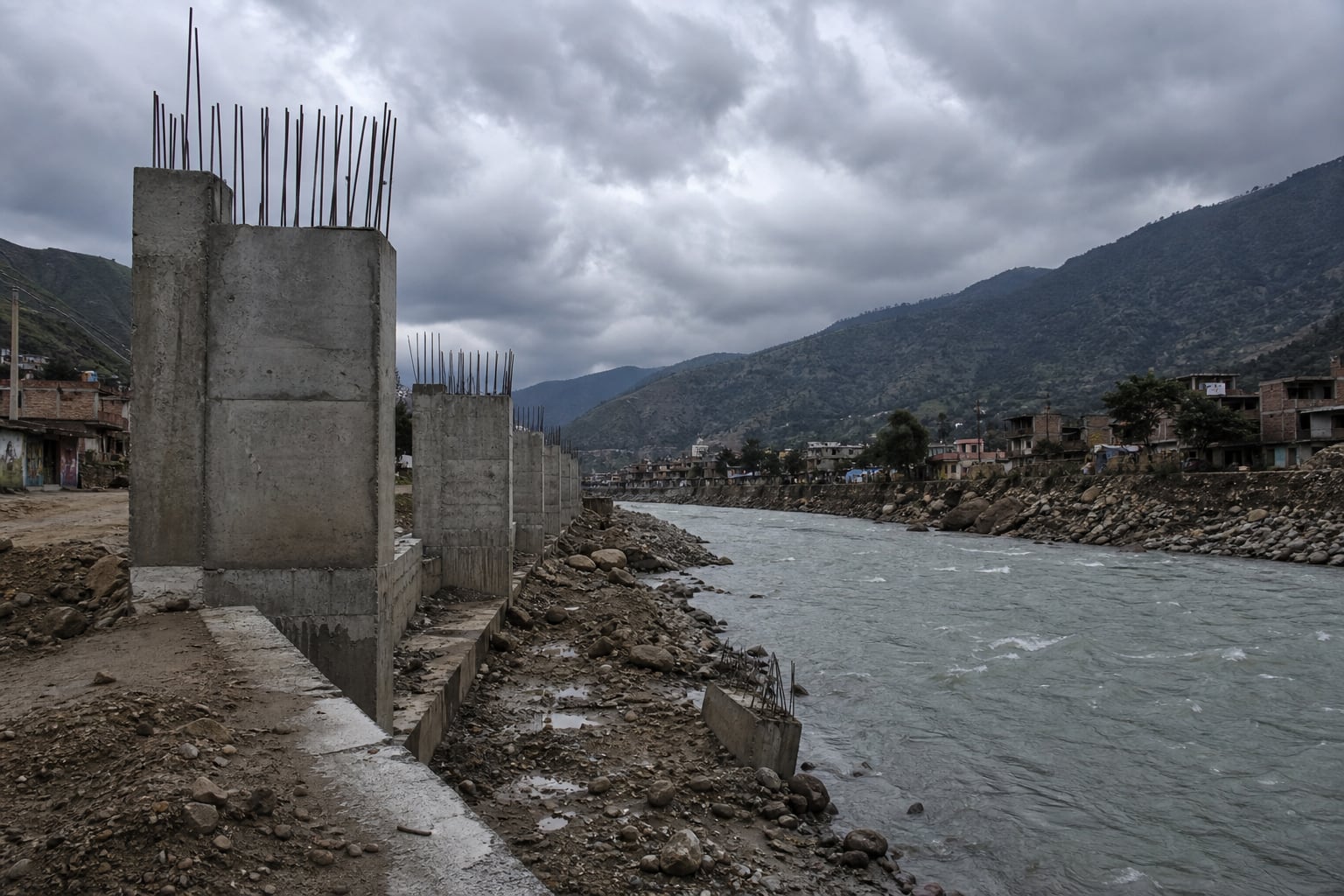 Una obra de concreto para defensa ribereña permanece inconclusa a orillas de un río cercano a viviendas rurales en un valle. (Imagen Ilustrativa Infobae)