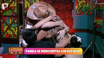 Pamela López, de espaldas y con un sombrero de cowboy, abraza a sus dos hijos en un escenario de televisión con paredes coloridas y grafitis