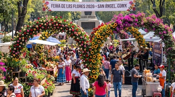 Personas transitan entre arcos florales con rosas, girasoles y buganvilias en la Feria de las Flores 2026 en San Ángel, Ciudad de México.