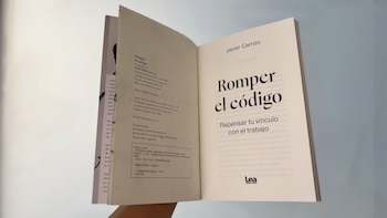 Primer plano de un libro abierto con las páginas interiores expuestas, mostrando el título 'Romper el código' y el nombre del autor 'Javier Carrizo'