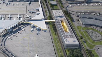 Vista aérea de un aeropuerto moderno con varias terminales, aviones blancos estacionados en las pistas, y un edificio alargado con un gran jardín interior visible desde arriba