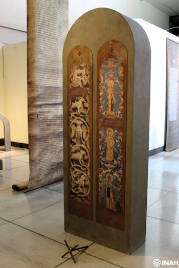 Estructura rectangular arqueada con dos paneles. El izquierdo, relieves zoomorfos. El derecho, figuras religiosas. Rollo de pergamino al fondo. Suelo de baldosas y objeto de metal pequeño
