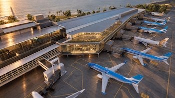 Vista aérea de una terminal de aeropuerto moderna con aviones de pasajeros estacionados en la pista junto al mar