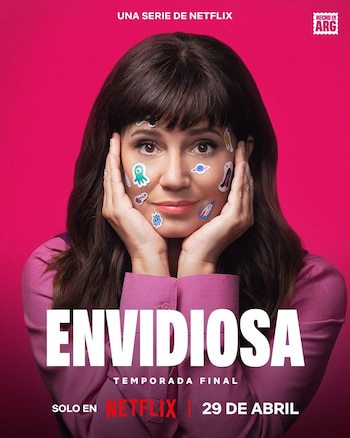 Mujer sonriente con cabello oscuro y flequillo, sosteniendo su rostro con ambas manos. Su cara está cubierta con pequeños stickers de figuras variadas