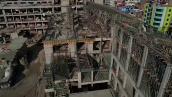 Vista aérea de una obra en construcción con encofrados y andamios colapsados sobre la estructura superior de un edificio de concreto