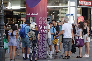 Varias personas forman una fila para rellenar botellas de agua en un caluroso día de verano en el centro de la ciudad de Viena, Austria, el sábado 27 de junio de 2026. (AP Foto/Heinz-Peter Bader)
