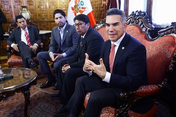 Cuatro hombres con trajes formales sentados en sillas ornamentadas en una sala. El hombre del primer plano, Alejandro Moreno, gesticula mientras habla. Se ve una bandera peruana al fondo