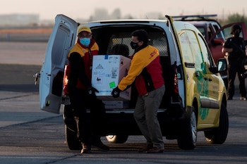 Dos trabajadores de un servicio de mensajería cargaban una caja con las primeras 10.000 dosis de la vacuna contra el COVID-19 en llegar a territorio chileno, el pasado 24 de diciembre. EFE/Alberto Valdés/Archivo