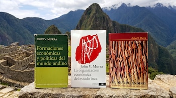 Tres libros colocados sobre un muro de piedra con las ruinas y montañas de Machu Picchu de fondo.