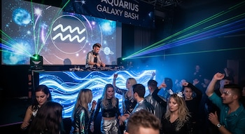 DJ actuando en una fiesta electrónica con temática de Acuario, público bailando y luces láser verdes.
