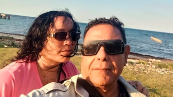Un hombre y una mujer con gafas de sol posan al aire libre frente al mar en un día soleado
