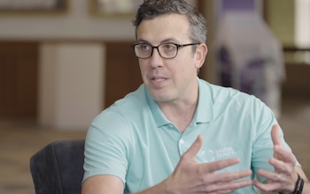 Un hombre con gafas y polo verde claro con el logotipo de Digital Realty gesticula con las manos
