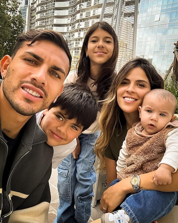Selfie frontal de Leandro Paredes, Camila Galante y sus tres hijos sonriendo. Él está a la izquierda; ella, a la derecha con un bebé. Dos niños mayores están en el centro
