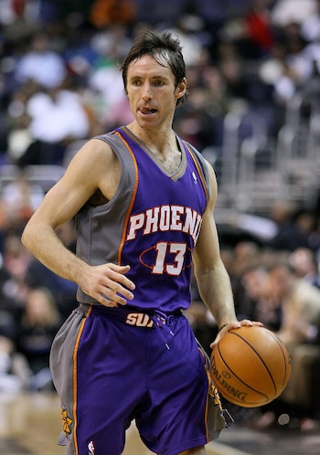 Steve Nash viste el uniforme morado y gris de los Phoenix Suns y bota un balón sobre la pista de baloncesto