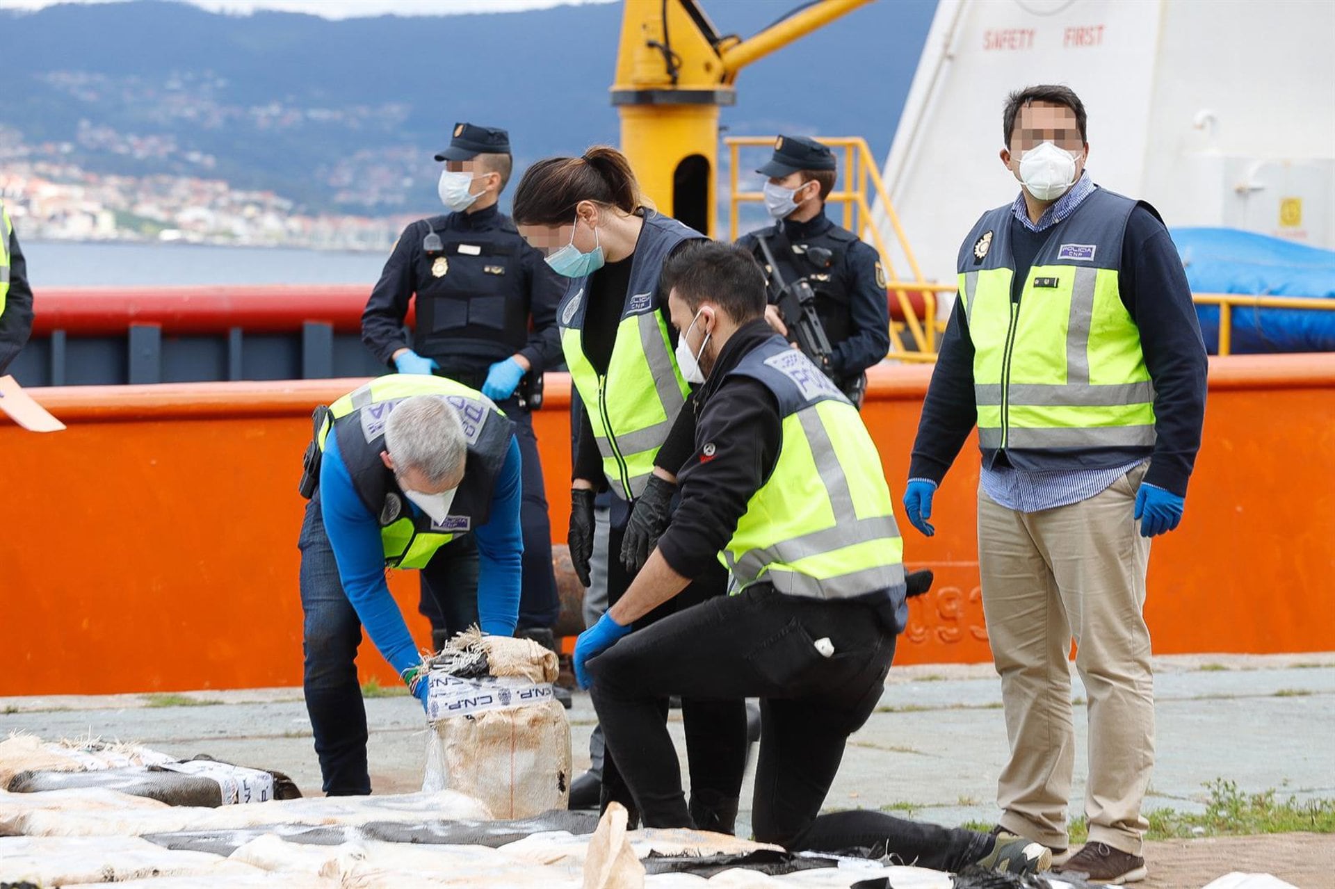Varios policías abren un saco con cocaína tras la llegada al Muelle de Cruceros del Puerto de Vigo de un buque mercante, en Vigo (Marta Vázquez Rodríguez./ Europa Press)
