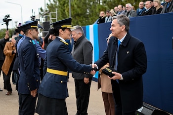 El gobernador Leandro Zdero, un hombre de cabello gris y traje oscuro, estrecha la mano de una oficial de policía uniformada en un evento al aire libre