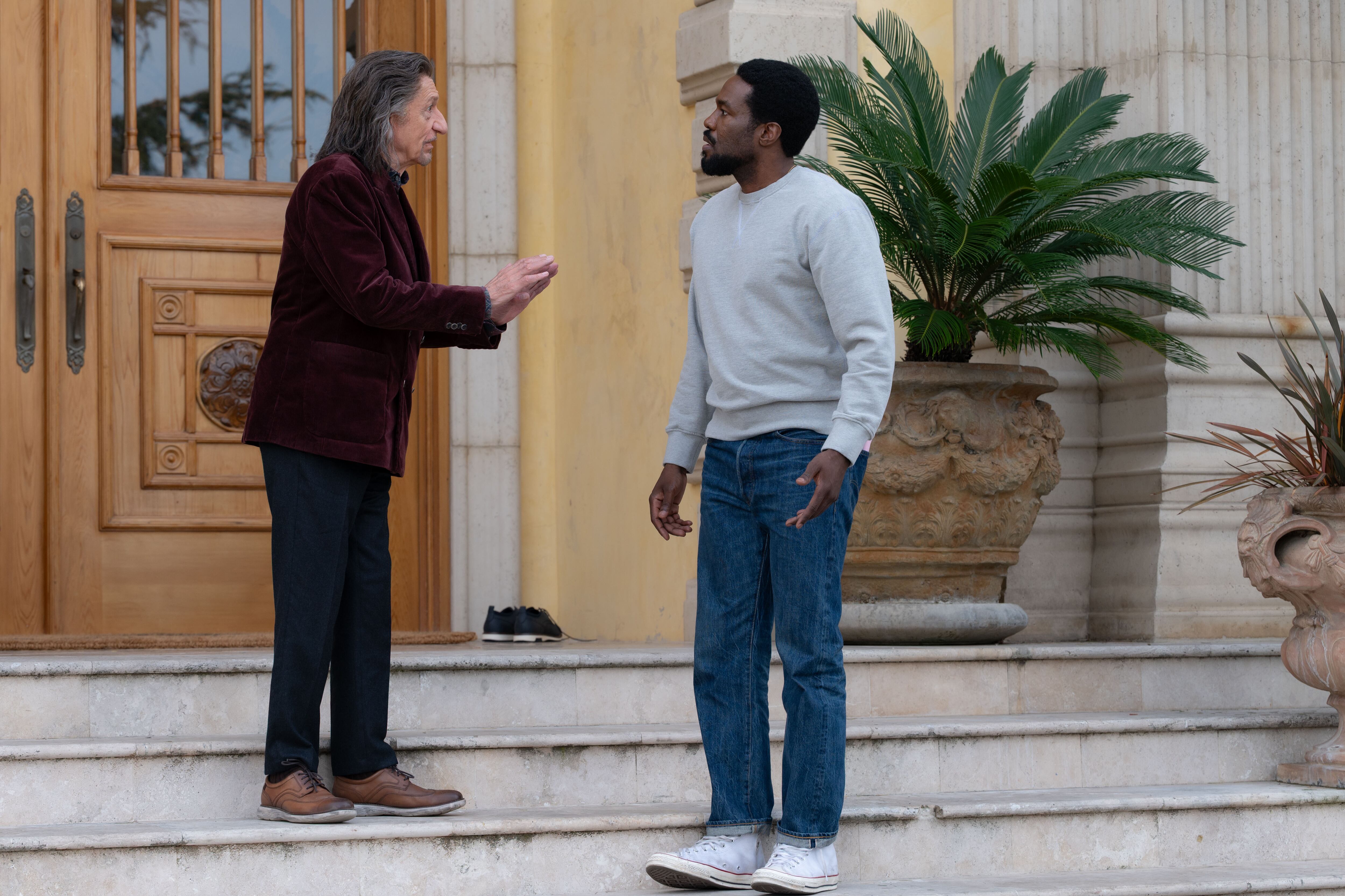 Ben Kingsley, en el papel de Trevor Slattery, y Wonder Man comparten un momento de discusión en una escalinata exterior, rodeados de vegetación y una imponente arquitectura (Disney Plus)