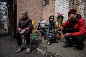 Aleksandra Vassilchenko (L) from Kramatorsk recounts her story as she sits with her grandson, Roman (R), outisde a shelter for internally displaced people, in Dnipro on April 16, 2022. - The elderly are "often forgotten, very vulnerable" during conflicts, says Federico Dessi, the director for Ukraine of the NGO Handicap International, which is providing equipment and financial support to the Dnipro shelter. (Photo by Ed JONES / AFP)