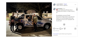 Dos hombres posan junto a una camioneta blanca con decoración de la selección argentina y Lionel Scaloni en una calle de noche, con edificios de fondo