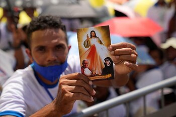 Un fiel sostiene una postal mientras espera en el parque de Tacitolu la misa del Papa Francisco en Dili.