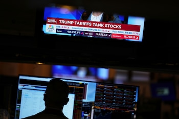 Una pantalla muestra noticias mientras los corredores trabajan en la Bolsa de Valores de Nueva York (AP Foto/Seth Wenig)