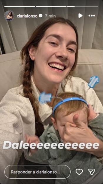 Mujer sonriente con cabello trenzado y un niño pequeño. El niño viste una diadema azul con dos pequeñas camisetas de rayas celestes y blancas