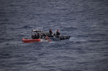 Una lancha semirrígida de la Guardia Costera de Estados Unidos se encuentra junto a un bote gris con varios ocupantes en mar abierto