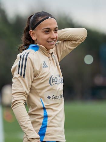 La jugadora Camila Ochoa sonríe mientras viste la ropa oficial beige y azul de la selección argentina