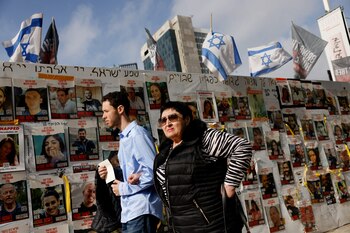 Personas pasan junto a carteles con fotos de los rehenes secuestrados en el mortífero atentado del 7 de octubre. (REUTERS/Carlos Garcia Rawlins)