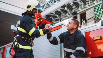 Unos bomberos se apoyan y