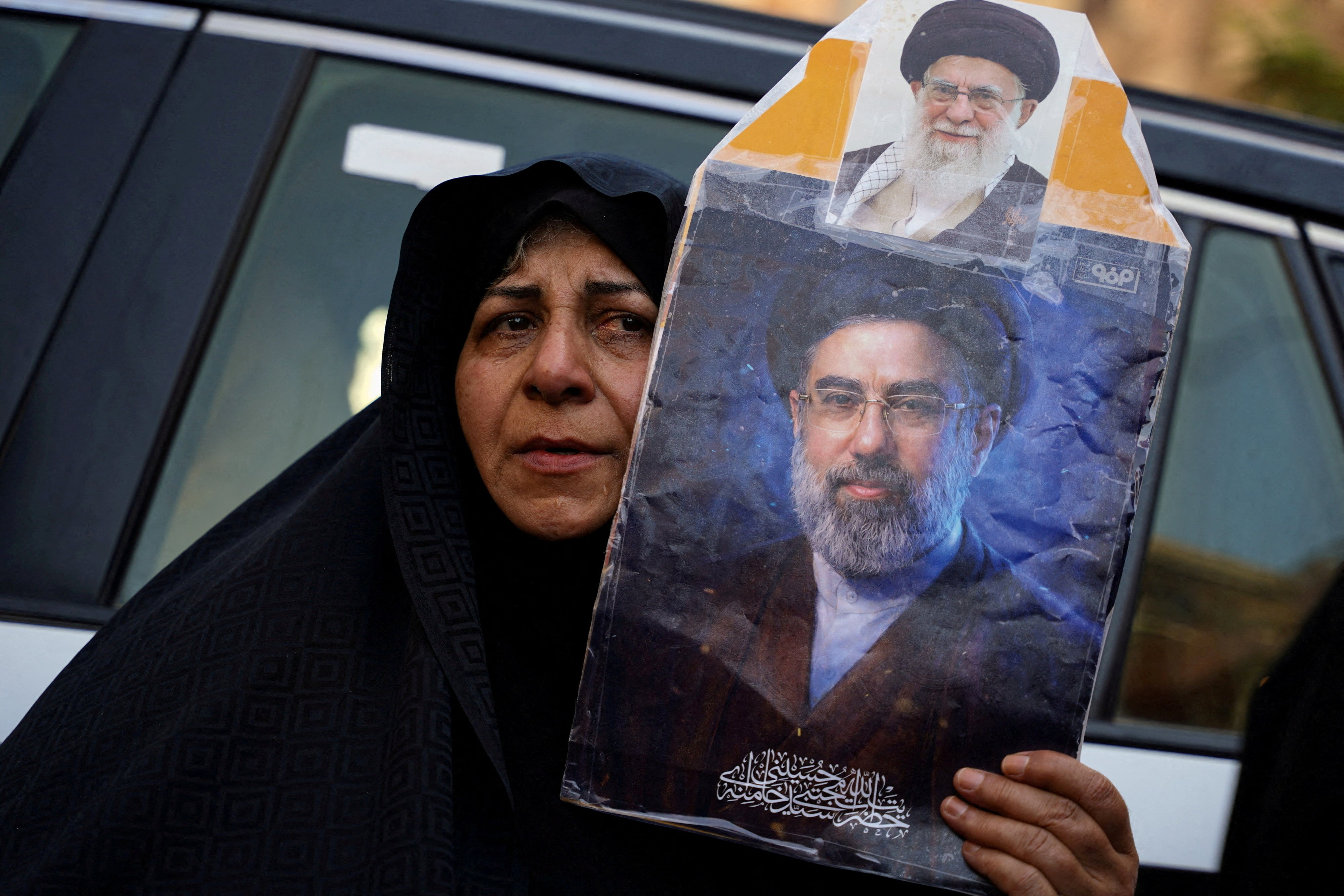 Una mujer sostiene un retrato del líder supremo de Irán, Mojtaba Khamenei, junto a otro del fallecido ayatolá Alí Khamenei, durante ceremonias fúnebres en Karbala, Irak (REUTERS/Teba Sadiq/archivo)