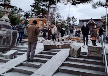 Un grupo de personas junto a una puerta torii derrumbada por un terremoto en el santuario de Onohiyoshi, en Kanazawa. (Kyodo via REUTER)