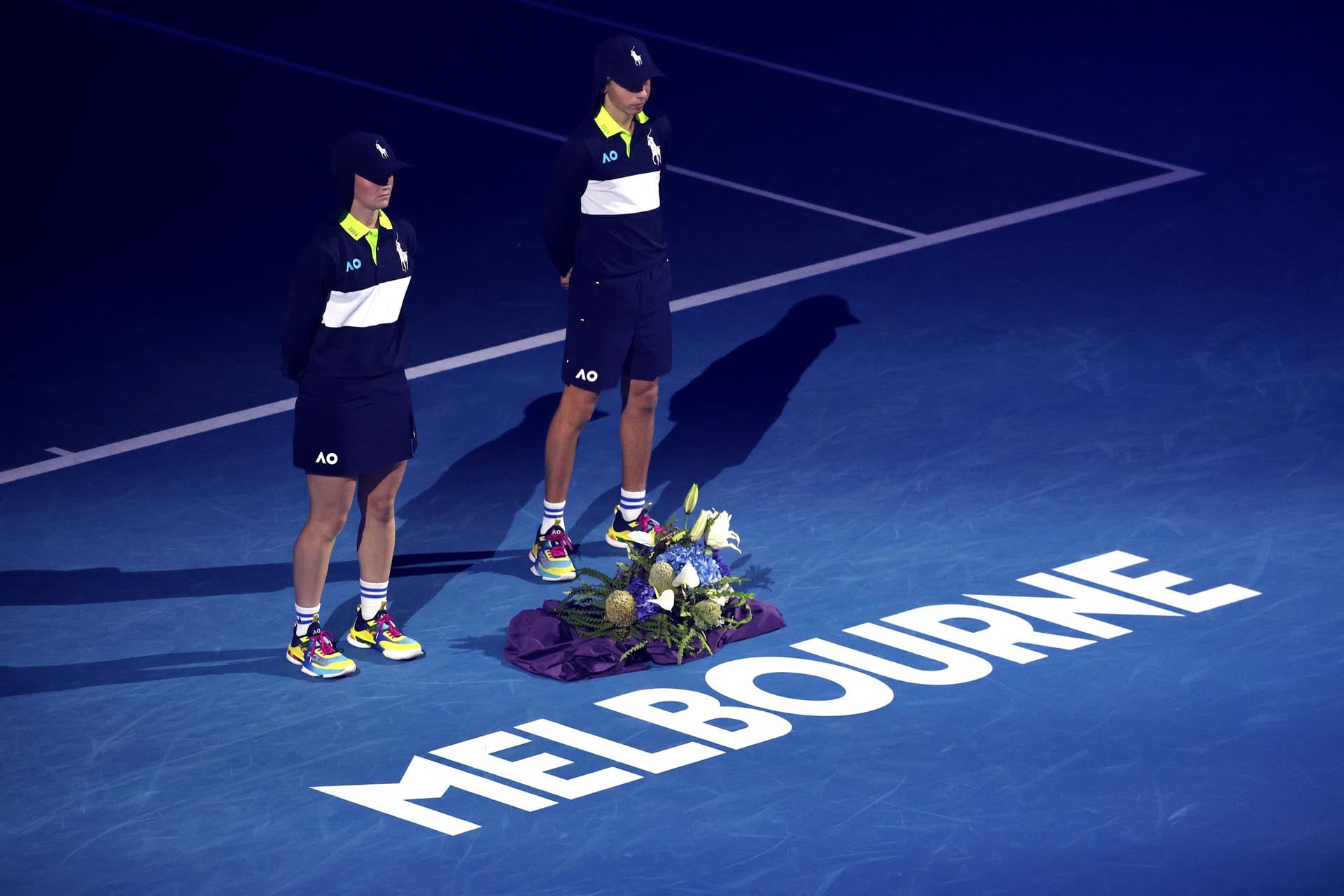 Los recogepelotas colocan un ramo de flores en la cancha del Rod Laver Arena durante un minuto de silencio en memoria de las víctimas del tiroteo de Bondi, durante el Día Nacional de Luto, el quinto día del Abierto de Australia, en Melbourne, el 22 de enero de 2026. (Foto: DAVID GRAY / AFP)