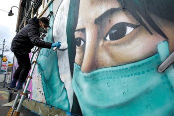 El artista callejero Carlos Giovanni, que firma como TheyDrift, trabaja sobre el retrato de una trabajadora de la salud para una pieza que lleva el nombre de "Quédate en casa", en Seattle, Washington. REUTERS/Jason Redmond