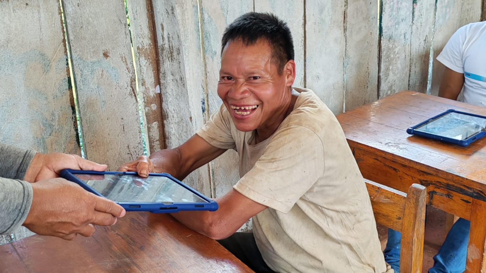 Un hombre en una zona rural del Perú recibe una tableta digital como parte de un programa de alfabetización para adultos mayores.