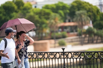 Dos personas con sombrilla y ropa veraniega durante una jornada de intenso calor en Sevilla. (María José López/Europa Press)